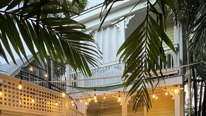 An outdoor patio with wicker furniture, string lights, and a view of the house.