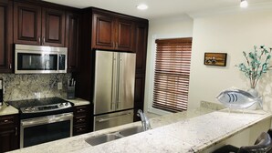 A modern kitchen with dark wood cabinets, stainless steel appliances, a granite countertop, and a built-in oven.
