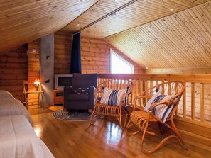 A cozy room with wooden walls and ceiling, a television, a sofa, and two rocking chairs. - Tahkon rantatupa 7 b by Interhome (Nilsiä)