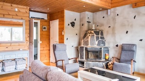 A cozy cabin interior with a stone fireplace, wooden walls, and a comfortable seating area. - Tahkon rantatupa 7 b by Interhome (Nilsiä)