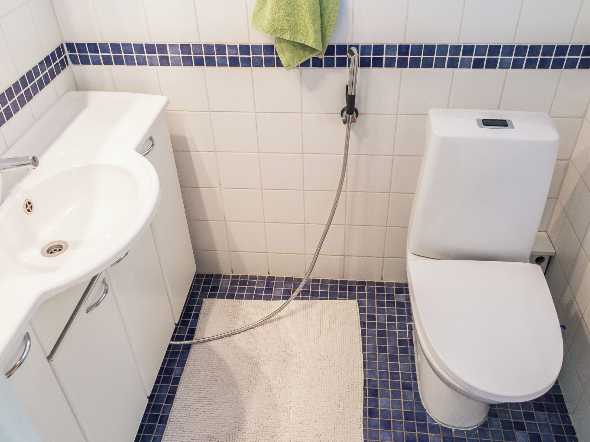 Een badkamer met een wit wastafelmeubel, toilet en douche.