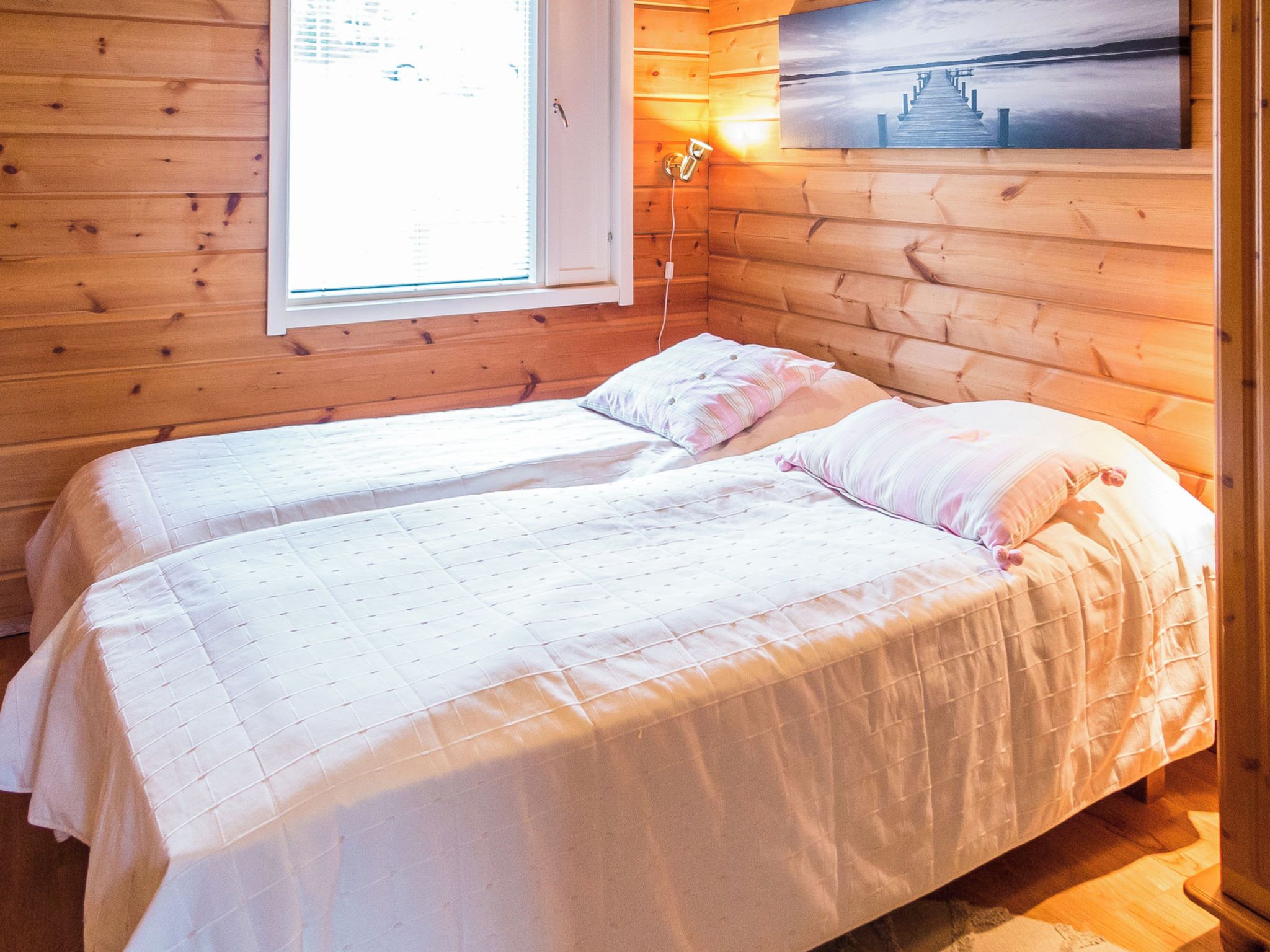 A cabin with two beds, a window, and a painting on the wall.