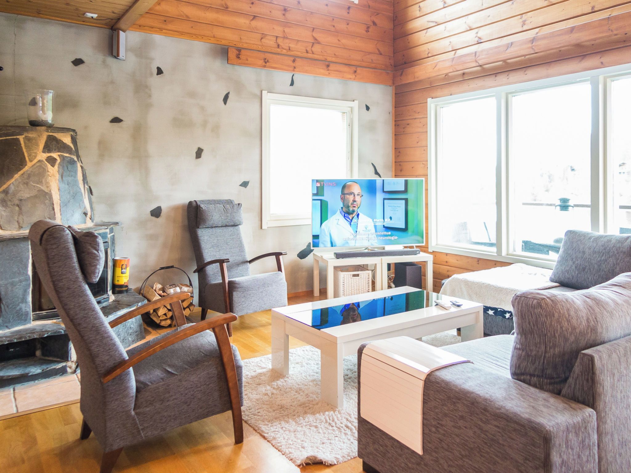 A cozy living room with a fireplace, comfortable seating, a television, and a large window providing natural light.