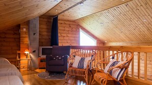 A cozy cabin interior with a wooden ceiling, a television, a sofa, and two rocking chairs. - Tahkon rantatupa 7 b by Interhome (Nilsiä)