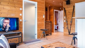 A cozy wooden interior with a television, a coffee table, and ski equipment. - Tahkon rantatupa 7 b by Interhome (Nilsiä)