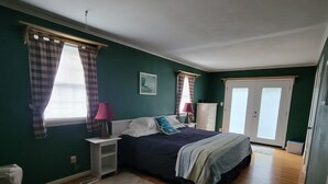 A bedroom with a bed, nightstands, a dresser, and a window with curtains. - A House Where Families Laugh, Cry and Just Be!!! (Jacksonville)
