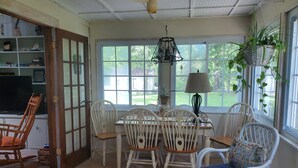 A dining area with a table and chairs, a television, and a window with a view of the outdoors. - A House Where Families Laugh, Cry and Just Be!!! (Jacksonville)