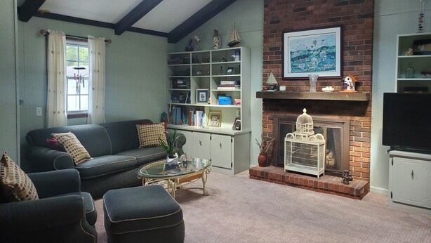 A living room with a fireplace, a sofa, a coffee table, and a bookshelf. - A House Where Families Laugh, Cry and Just Be!!! (Jacksonville)