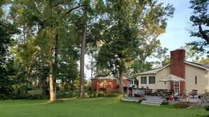 A house with a brick chimney, a porch with outdoor furniture, and a well-maintained lawn. - A House Where Families Laugh, Cry and Just Be!!! (Jacksonville)