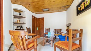 Un salon au plancher de bois, comprenant un coin repas, une porte en bois et une chaise bleue.