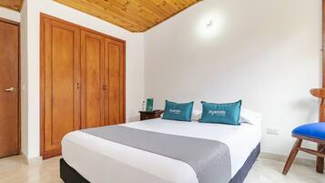 Un dormitorio con una cama grande, un armario de madera y una silla.