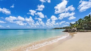Una playa con agua turquesa cristalina, una orilla de arena y una hilera de palmeras.
