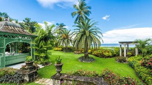 Un jardín exuberante con palmeras, un mirador y vista al océano.
