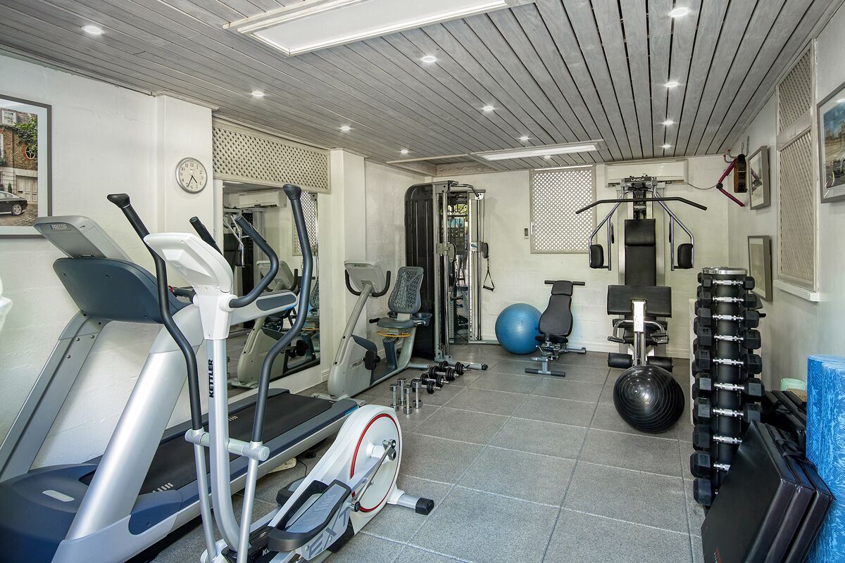 A gym with treadmills, elliptical machines, free weights, and exercise balls.