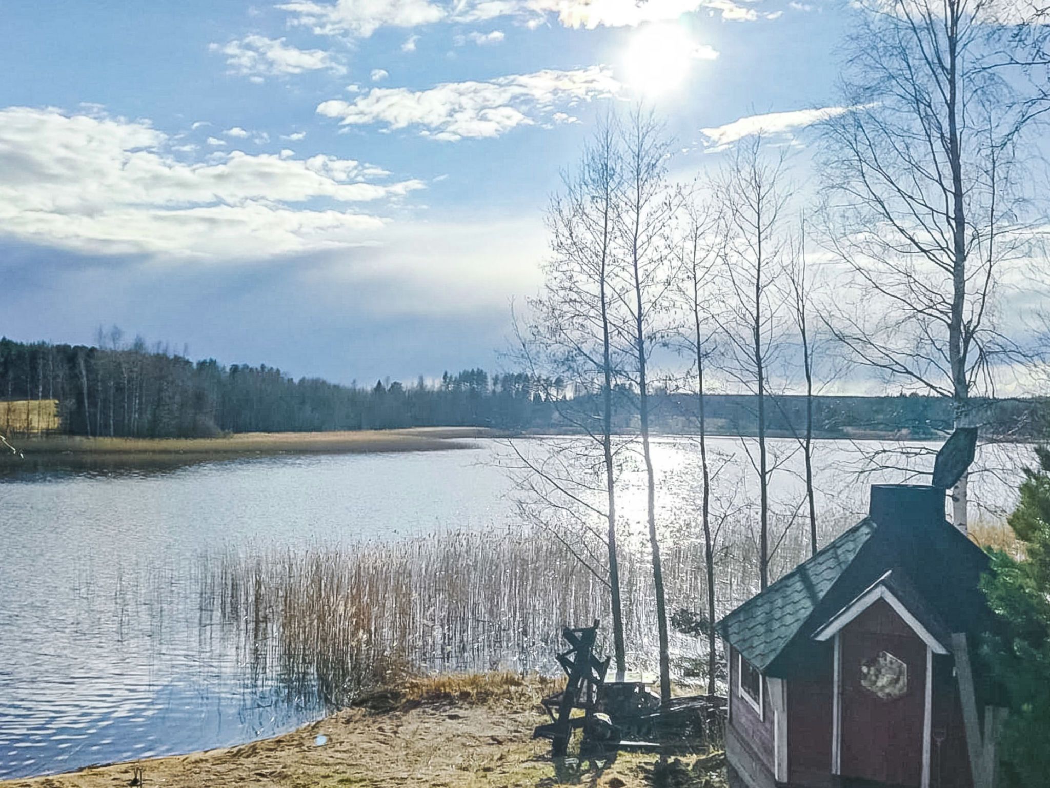 A lakeside view with a cabin and a dock extending into the water.