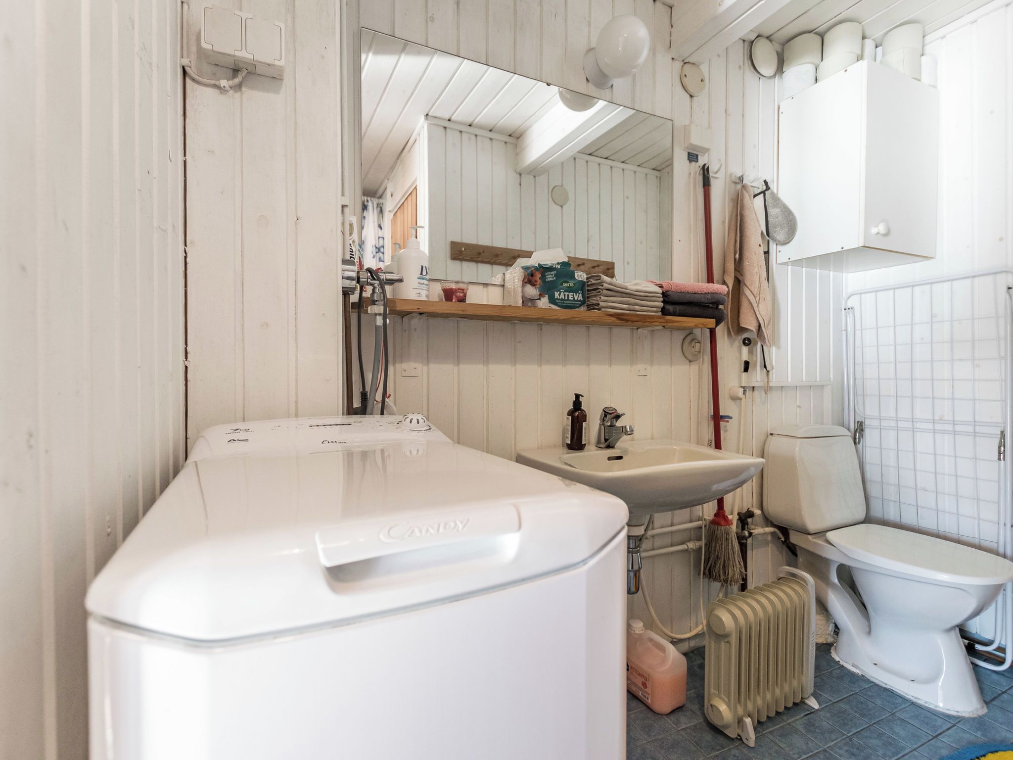 A compact bathroom with a white sink, toilet, and a washing machine.