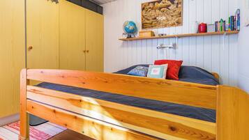 A bedroom with a wooden bed, a globe, a shelf with books, and a painting on the wall.