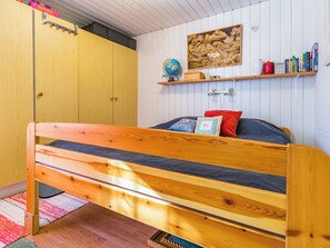 Un dormitorio con una cama de madera, un globo terráqueo, una estantería con libros y un cuadro en la pared.