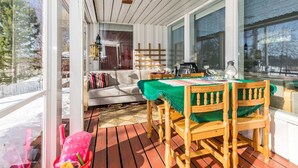 En træterrasse med et bord, stole og en sofa, samt udsigt til det fri.