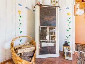 A room with a vintage-style refrigerator, a woven basket with firewood, and a small lantern.