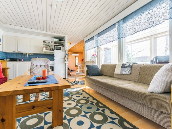 A cozy living area with a wooden table, a sofa, and a kitchen in the background.