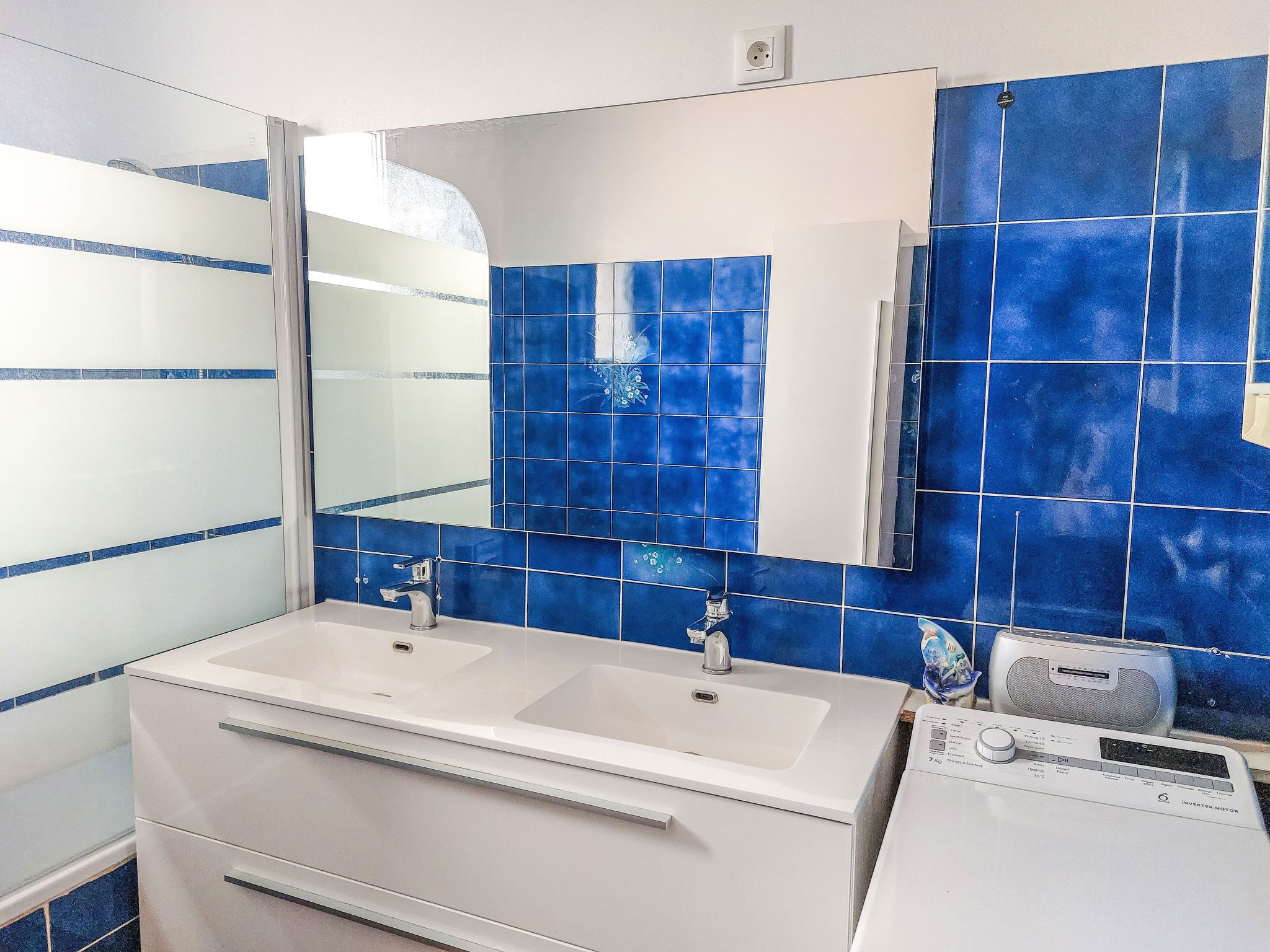 Une salle de bain avec deux lavabos, un miroir et un meuble blanc.