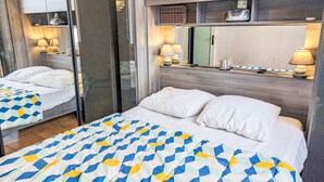 Een slaapkamer met een bed, nachtlampjes, een spiegel en een dressoir.
