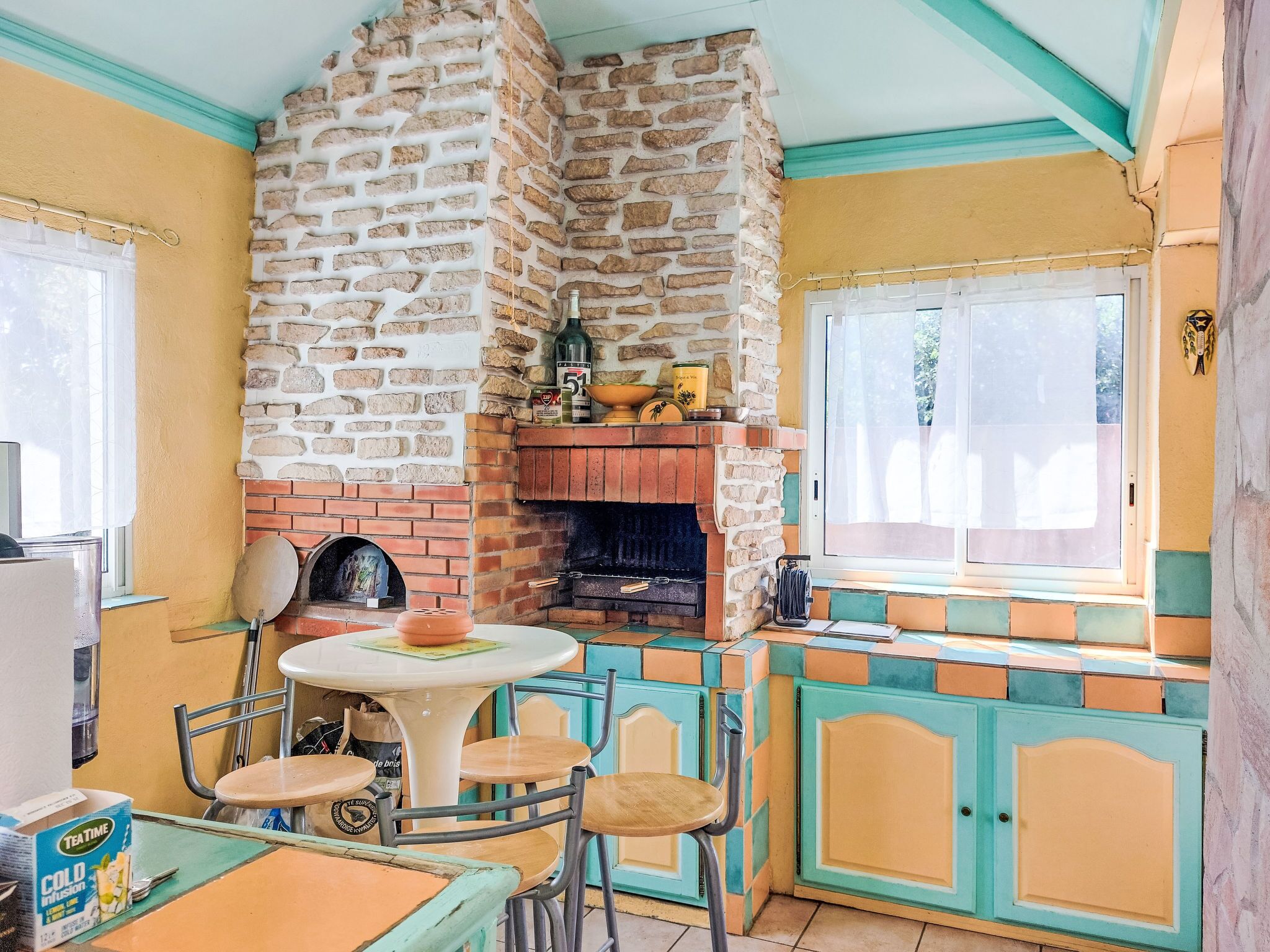 A cozy kitchen with a stone wall, a brick fireplace, and a dining area with a table and chairs.