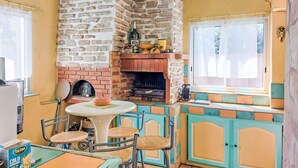 Een gezellige keuken met een stenen muur, een schouw van baksteen en een eethoek met een tafel en stoelen.