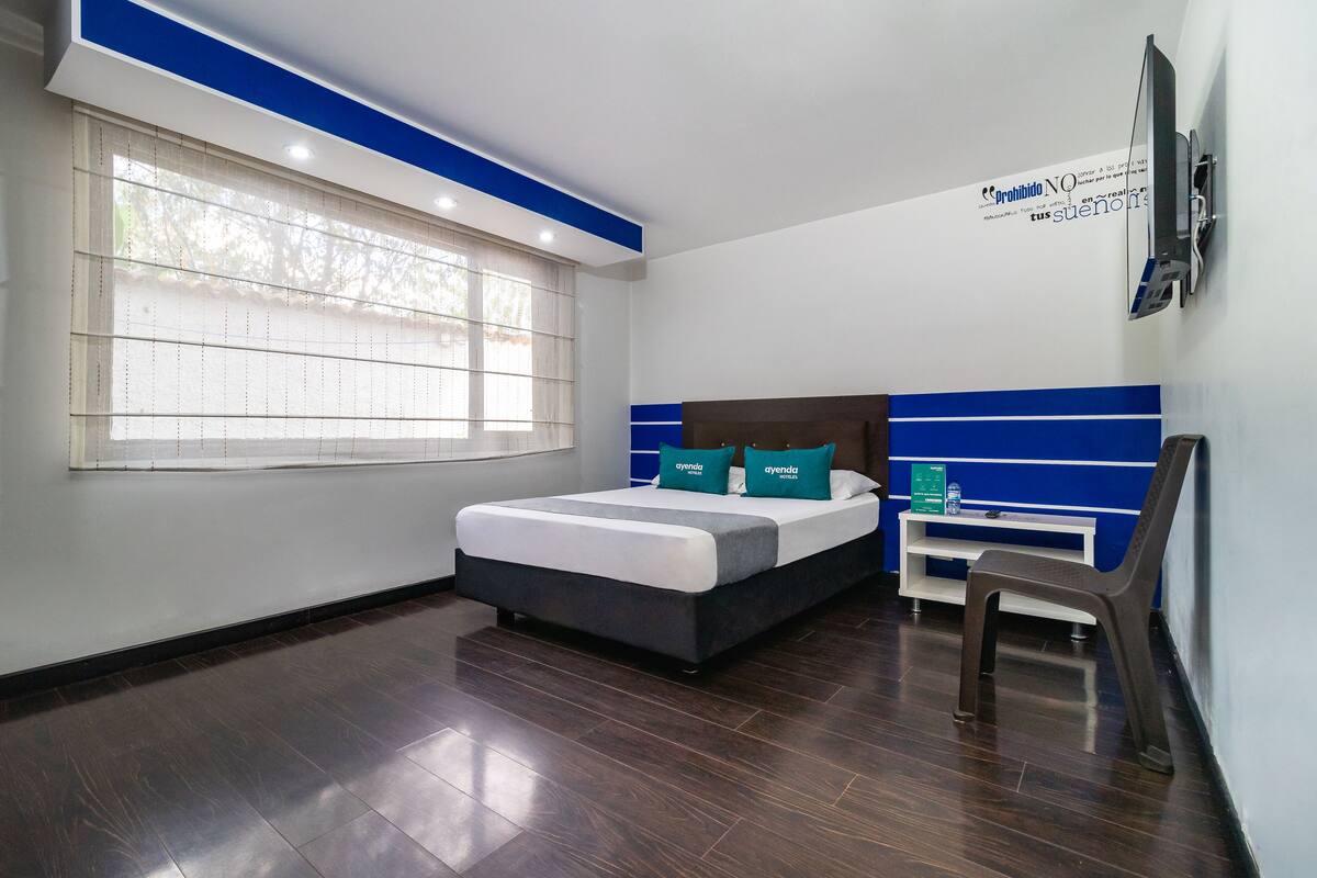 Une chambre d’hôtel moderne, dotée d’un grand lit, d’un bureau et d’une chaise.