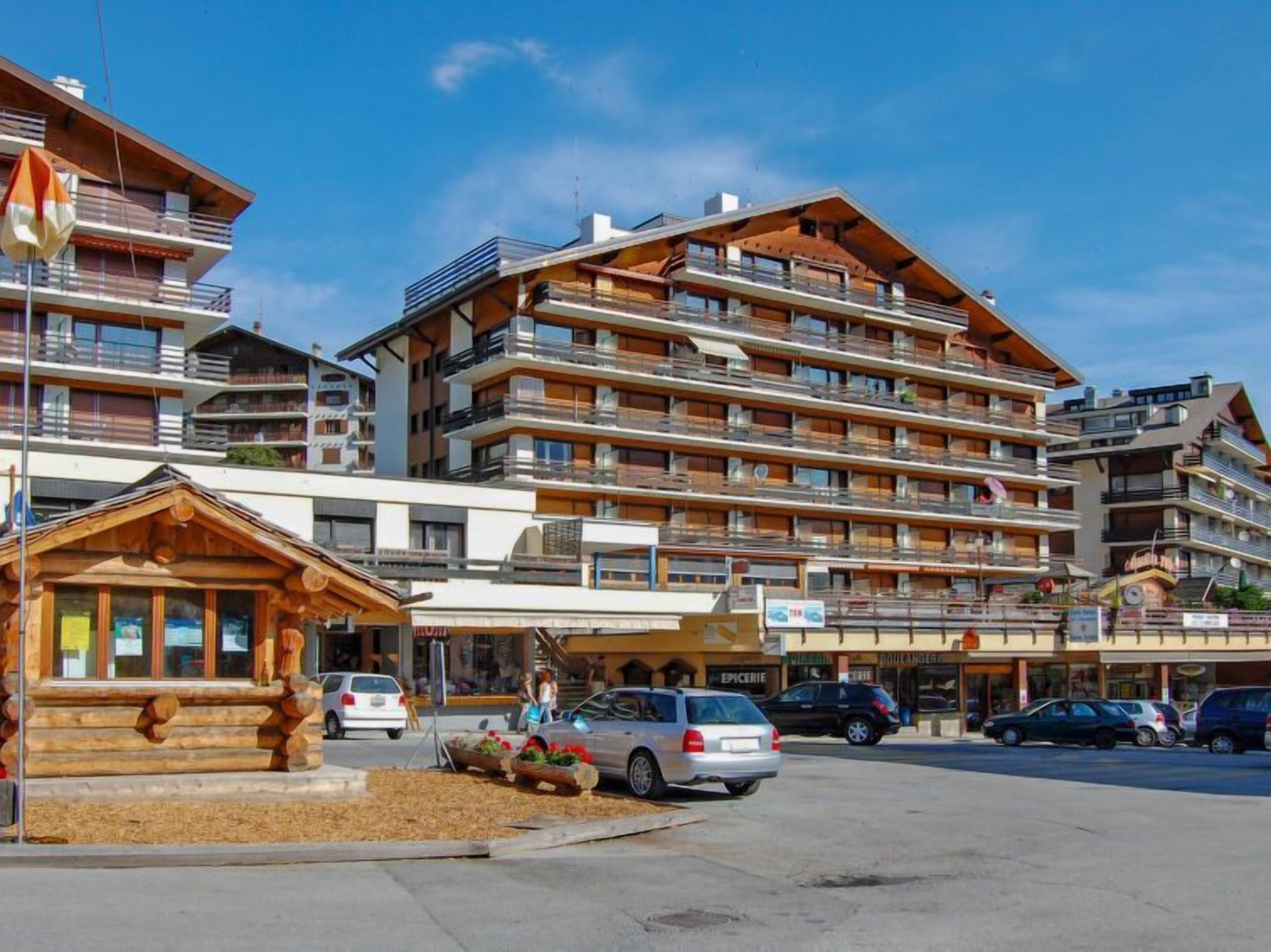 A multi-story hotel with balconies, a wooden facade, and a central entrance.