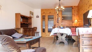 Una sala acogedora con un sofá de cuero marrón, una mesa de comedor de madera con mantel blanco y una araña.