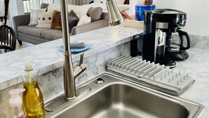 A modern kitchen with a stainless steel sink, a coffee maker, and a framed picture on the wall. - Oz Festival! Walk to Resort! Pets! Fireplace! (Beech Mountain)