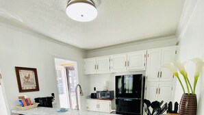 A modern kitchen with a marble countertop, wooden stools, a black refrigerator, and a white backsplash. - Oz Festival! Walk to Resort! Pets! Fireplace! (Beech Mountain)