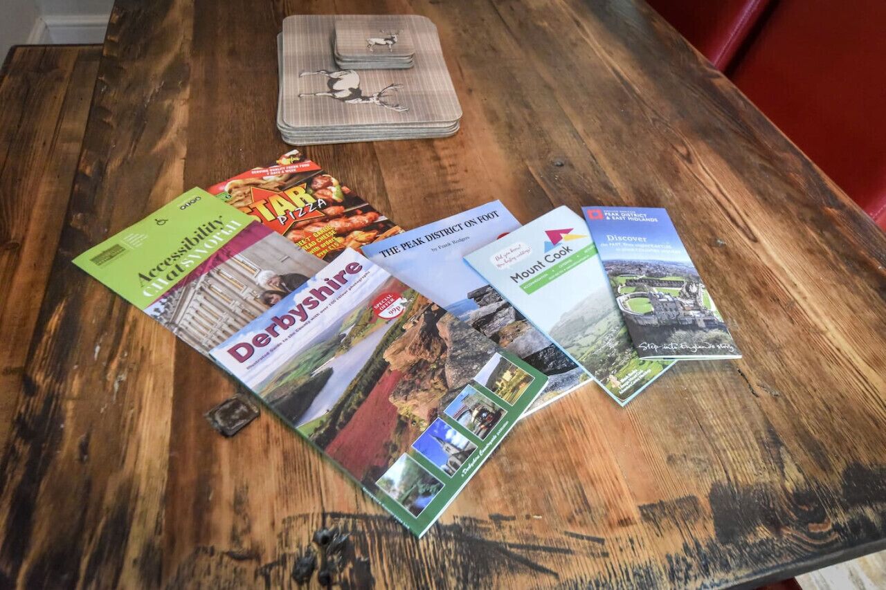 Ein Holztisch mit einigen Reisemagazinen und einer Brille.