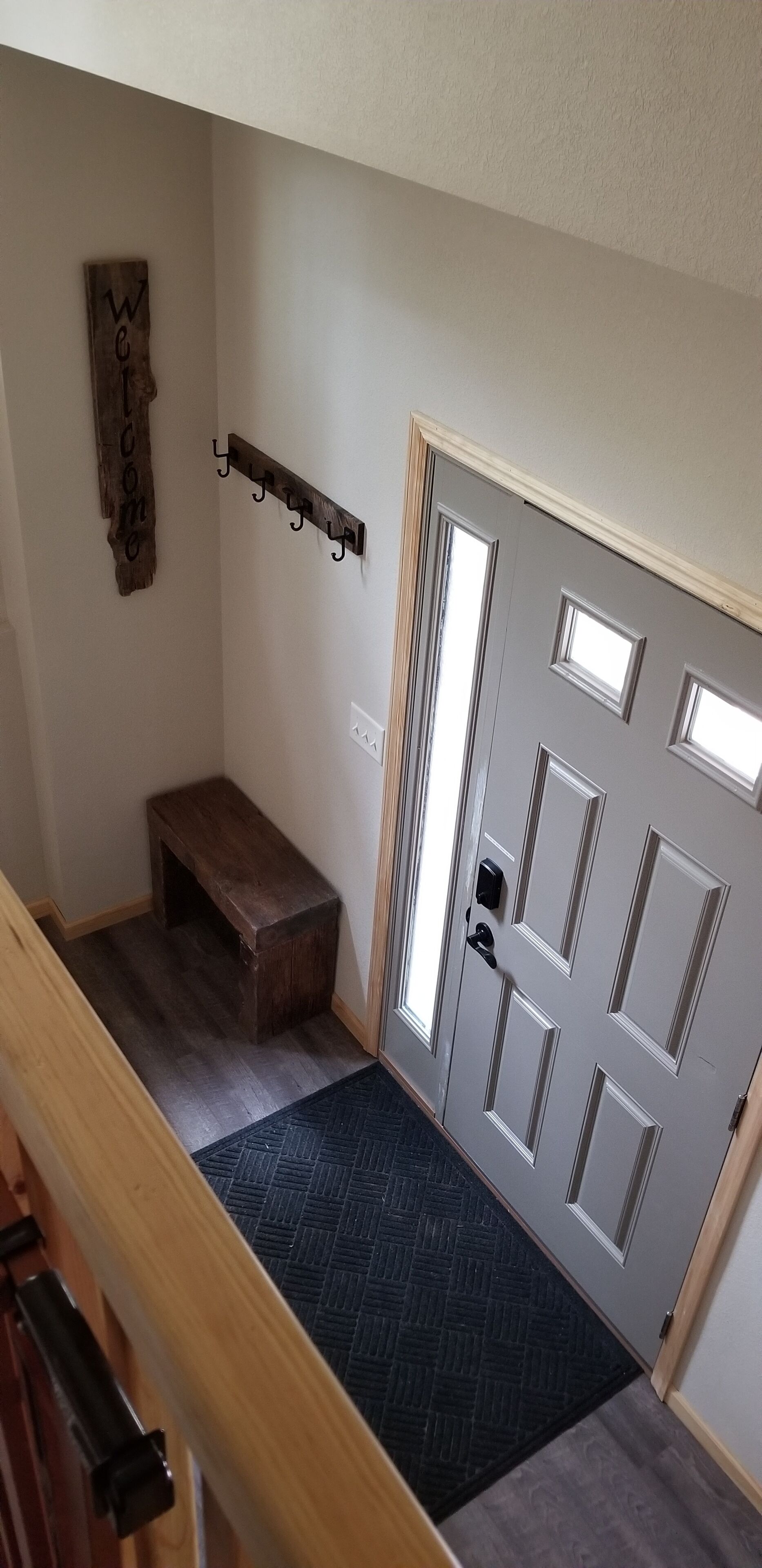 Un couloir avec un banc en bois, un porte-manteau et une porte dotée d’un judas.