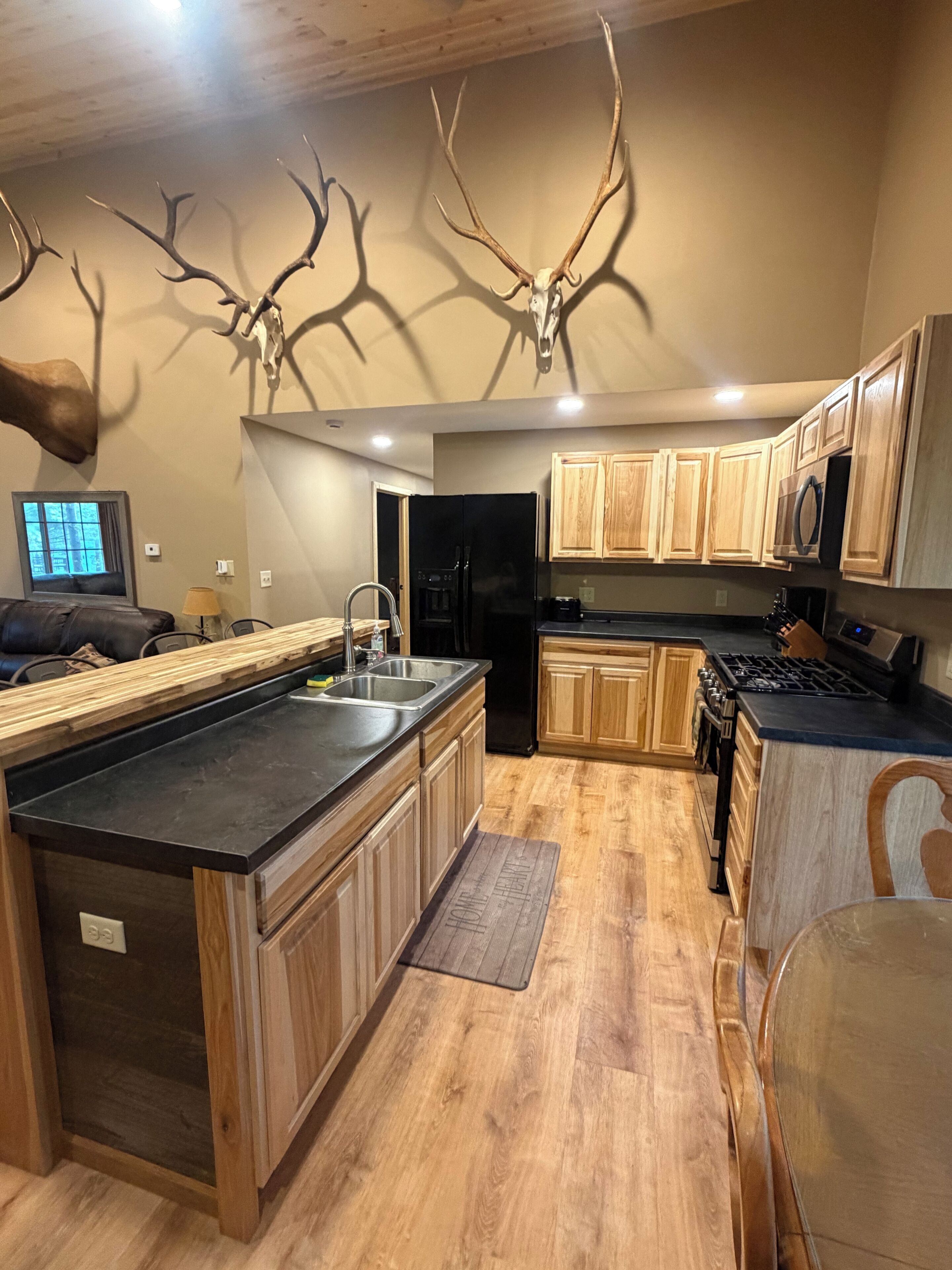 Une cuisine moderne avec des meubles en bois, un réfrigérateur noir et un grand îlot central.