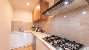 Une cuisine moderne avec une cuisinière à gaz, des armoires blanches et un plafond en bois.