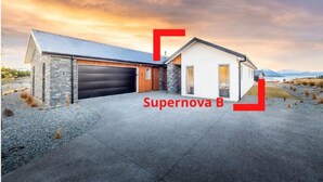Une maison moderne avec un garage, une façade en pierre et une allée.