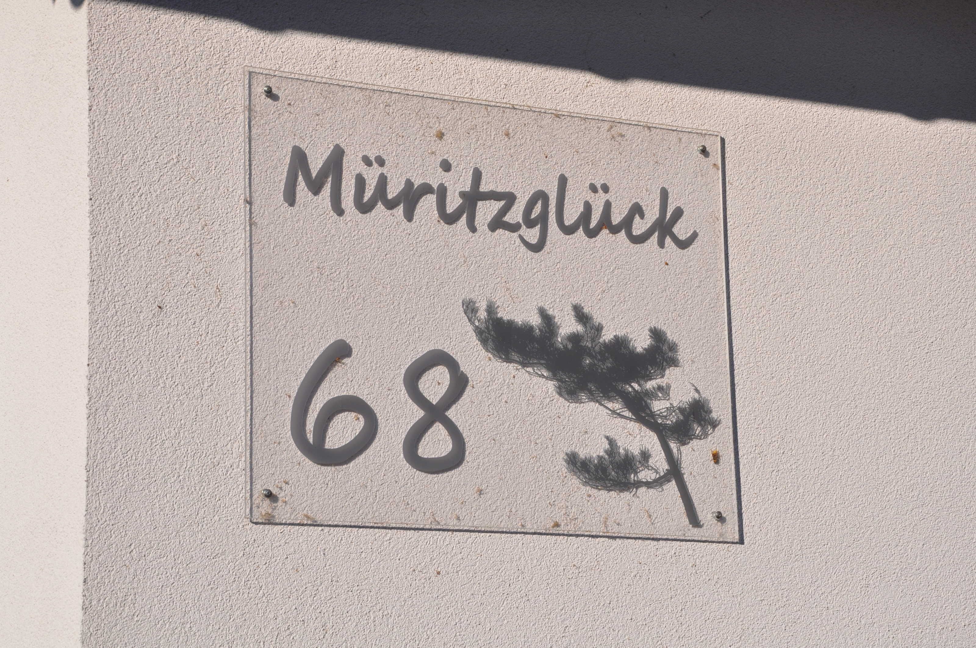 A sign with the text "Müritzglück 68" on a wall.