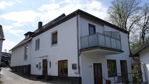 A two-story building with a balcony, a door, and a window.