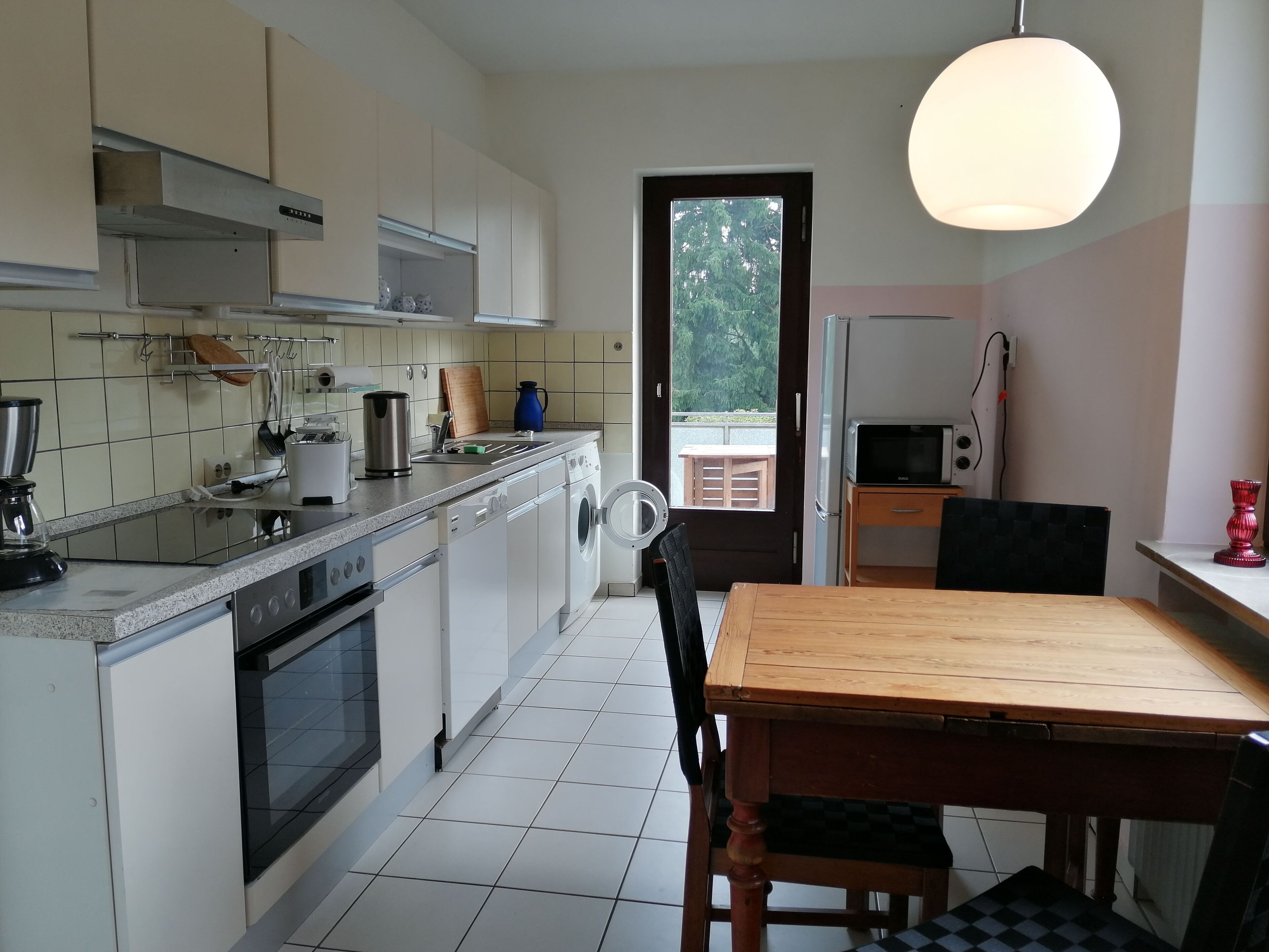 A compact kitchen with a dining area, a washing machine, and a microwave.