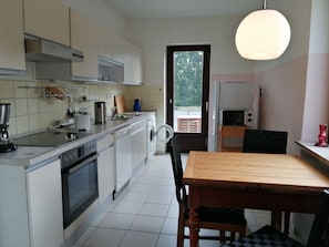 A compact kitchen with a dining area, a washing machine, and a microwave.