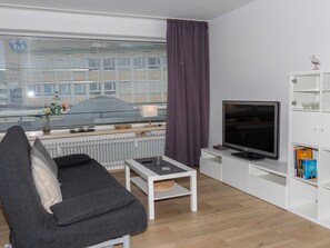 A modern living room with a sofa, a TV, a coffee table, and a bookshelf. - 077-2 Holiday apartment Jungmann - 077-2 Holiday apartment Jungmann (Wilhelmshaven)
