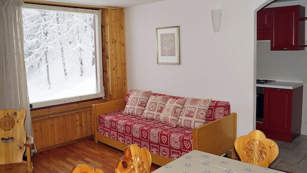A cozy room with a wooden bed, a dining table, and a kitchen area. - Maison Perchu - Pila, Vallée D'aoste (Pila)