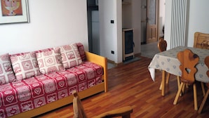 A cozy living room with a sofa, wooden dining table, and chairs. - Maison Perchu - Pila, Vallée D'aoste (Pila)