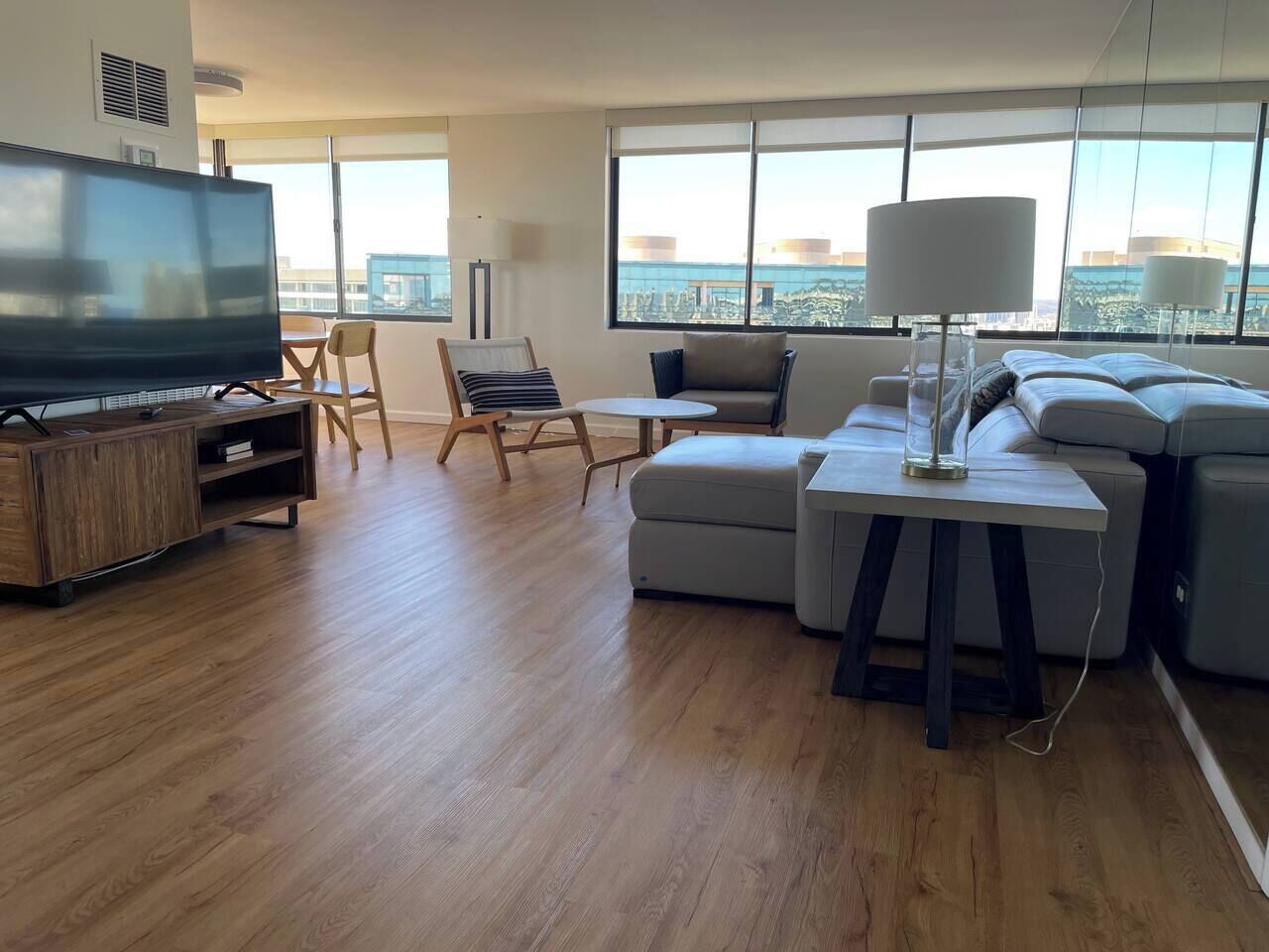 A modern living room with a flat-screen TV, a sofa, a small table, and a chair.