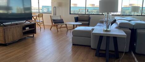 A modern living room with a flat-screen TV, a sofa, a small table, and a chair.