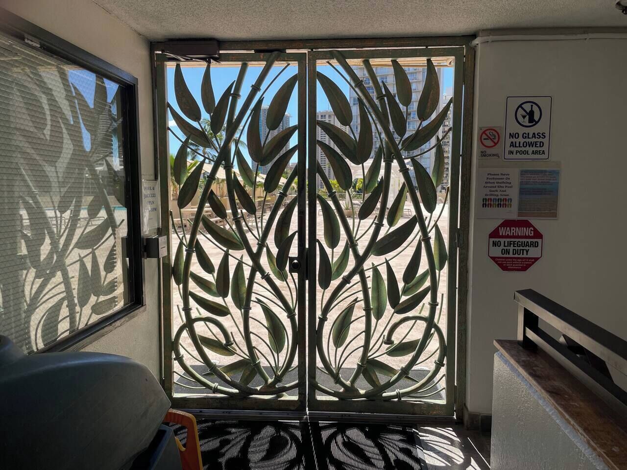 A room with a metal gate, a bench, and a view of buildings outside.