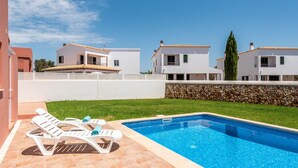 A swimming pool with lounge chairs and a stone wall.